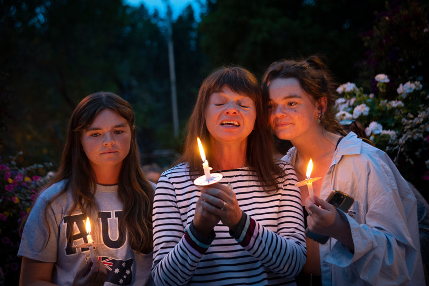 Sally Glass,center, mother of 22-year-old Christian Glass who was shot by police after calling 911 for help, is flanked by his sisters Katie, left, and Anna, right as they attend a candlelight vigil in Idaho Springs, Colorado Sept. 20, 2022.